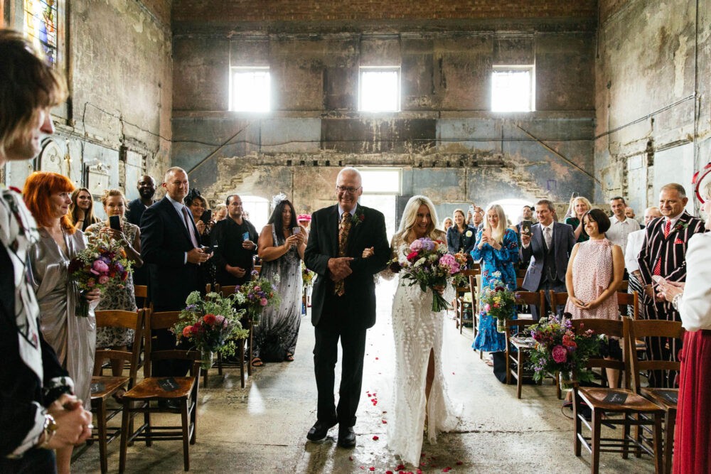 a bride is walked down the aisle at the asylum chapel buy her father